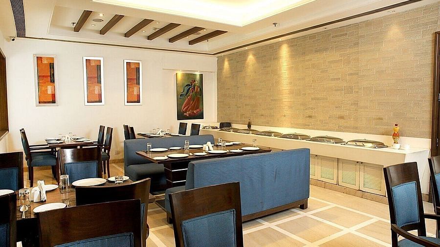 Tables and chairs neatly arranged with cutlery set on the table at Café Inde, Inde Signature Tower, Gurgaon