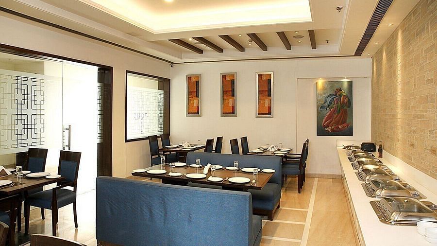 Tables and chairs neatly arranged with cutlery set on the table at Café Inde, Inde Signature Tower, Gurgaon