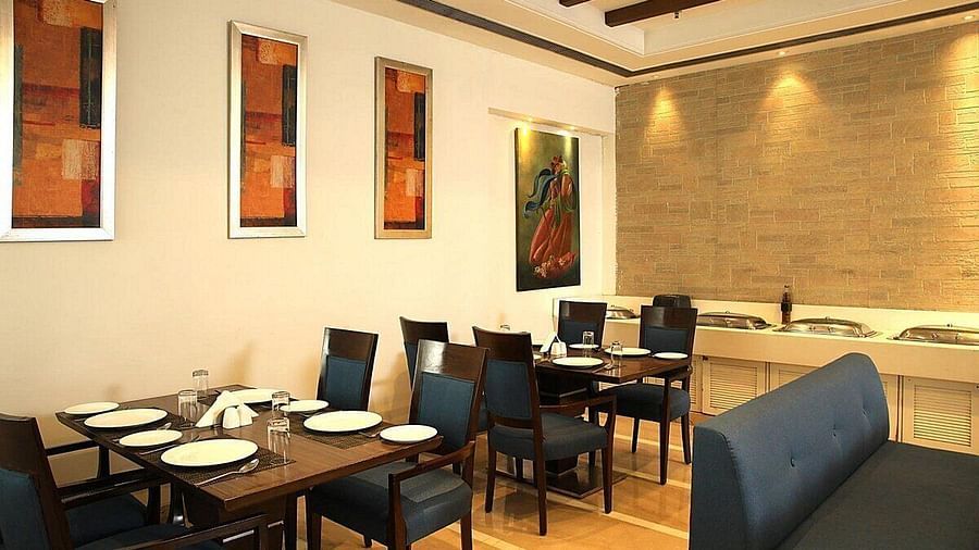 Tables and chairs neatly arranged with cutlery set on the table at Café Inde, Inde Signature Tower, Gurgaon