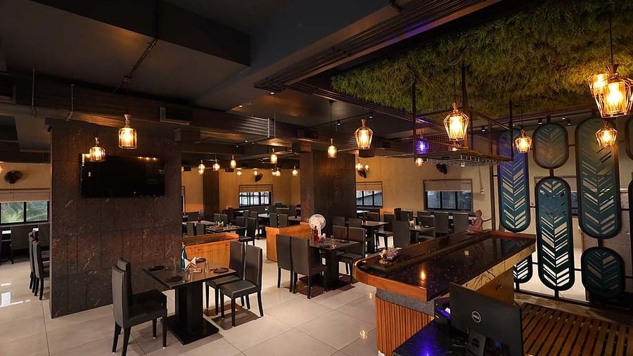 The image captures the ambiance of a restaurant featuring tables, chairs, a bar area, and decorative lighting - Lords Eco Inn Navsari.