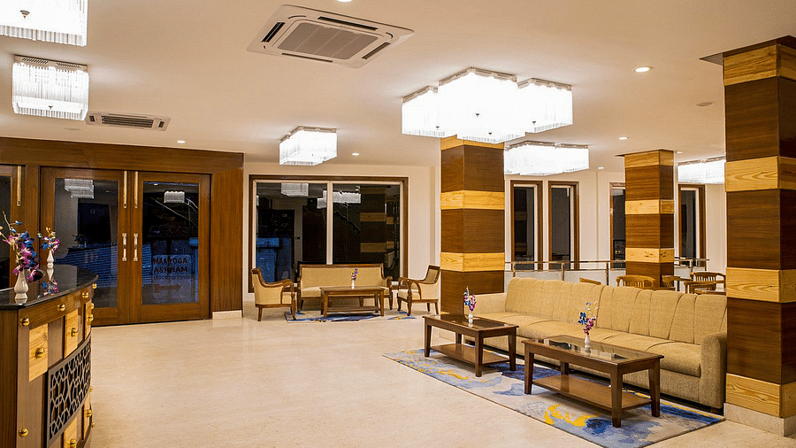 Corner view shot of the expansive lobby at Regenta Inn DLS with beige coloured couches kept in the waiting area.