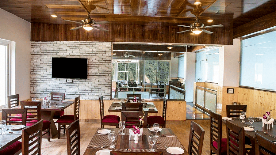 Front view shot of the dining area with a shiny wooden ceiling at Regenta Inn DLS.