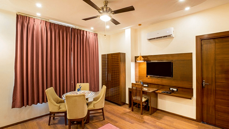 The living area at the Suite with a dining table, a wardrobe, and a wall mounted television at Regenta Inn DLS.