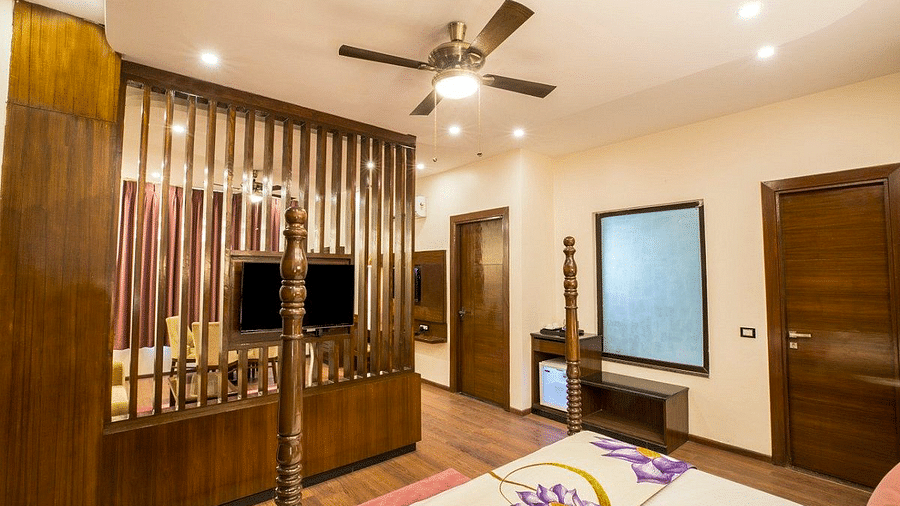 Corner view shot of the bedroom at the Suite with a wall mounted television on the wooden partition at Regenta Inn DLS.