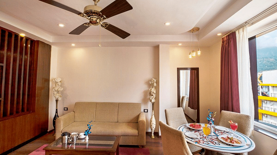 Front view shot of the living area featuring a couch along with a coffee table and a dining table besides it in the Suite at Regenta Inn DLS.
