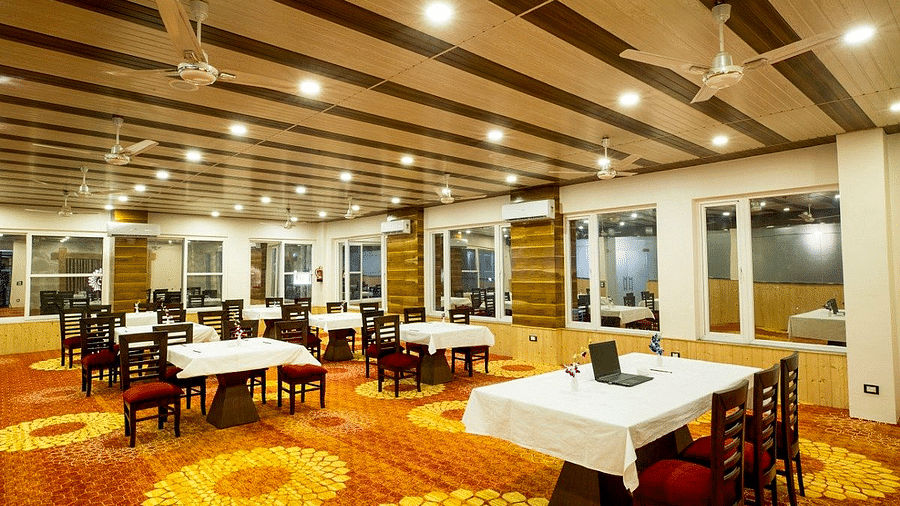 Corner view shot of the banquet hall at Regenta Inn DLS with panel lights and ceiling fans attached on the ceiling.