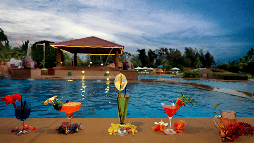 Bright coloured drinks are assembled in front of an exceptionally blue pool