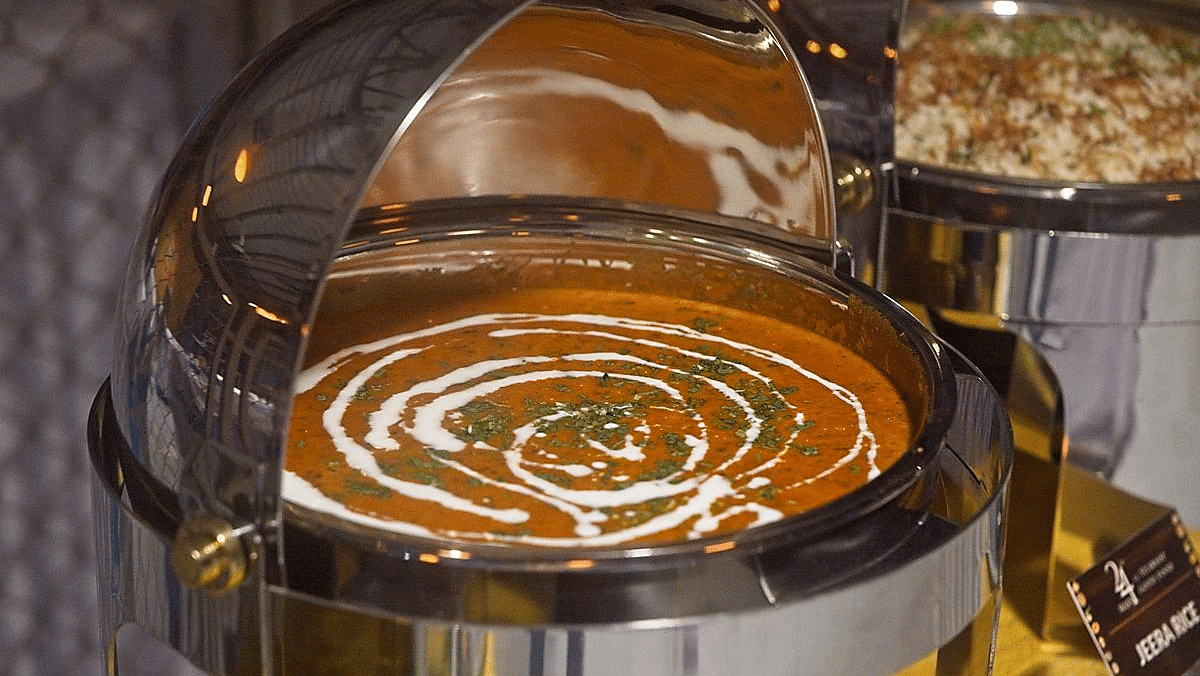 Close-up of a chafing dish with creamy sauce and a swirl design on top.