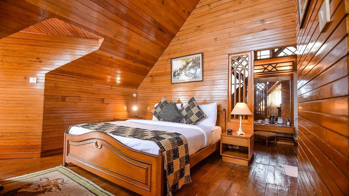 Furnished with a double bed, bedside table and wooden interiors, the spacious observatory suite in Cedar Inn, Darjeeling has good ventilation.