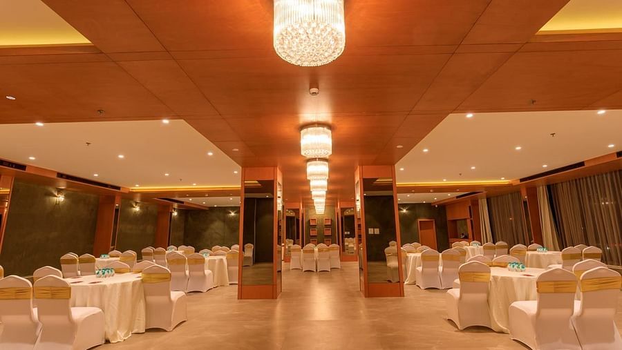 large banquet hall at Lords Eco Inn Apple Gate is set up with round tables and draped chairs