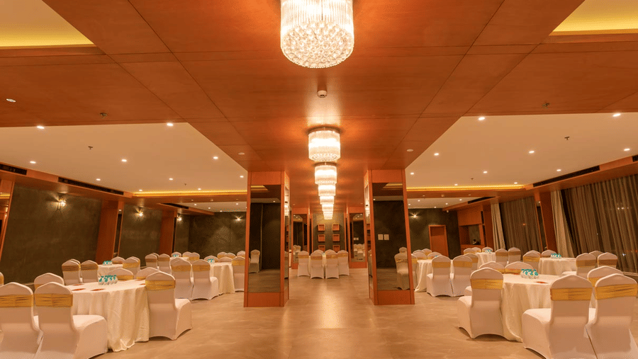large banquet hall at Lords Eco Inn Apple Gate is set up with round tables and draped chairs