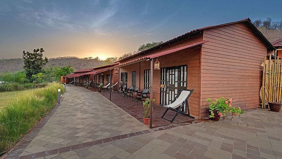 A row of identical wooden cabins with red roofs stretches into the distance under a late afternoon sky.