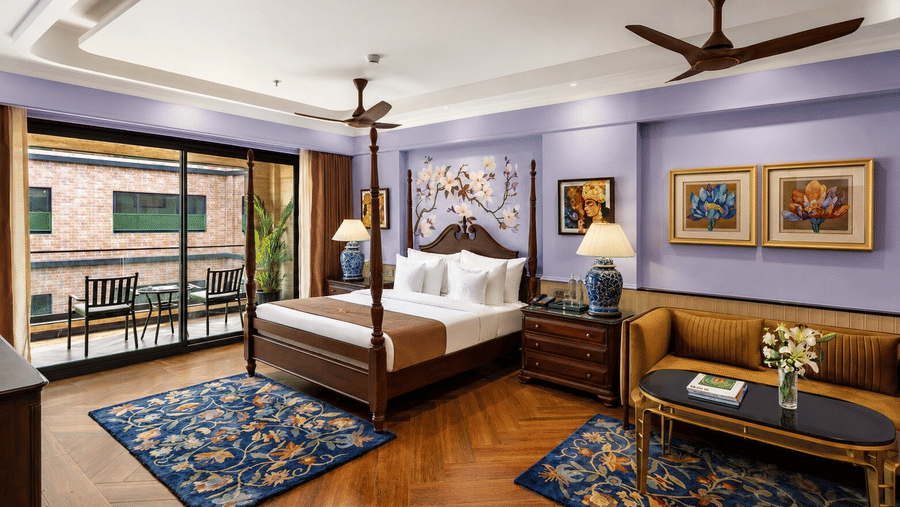A wooden 4-poster bed, patterned carpets and a seating area in a Luxury Villa at MAYFAIR Bay Resort, Paradeep.