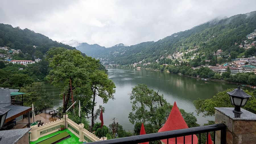 Stunning lake view from Himalaya Hotel, Nainital overlooking Naini Lake with hillside homes, boats on water, and dramatic cloudy mountain scenery beyond.