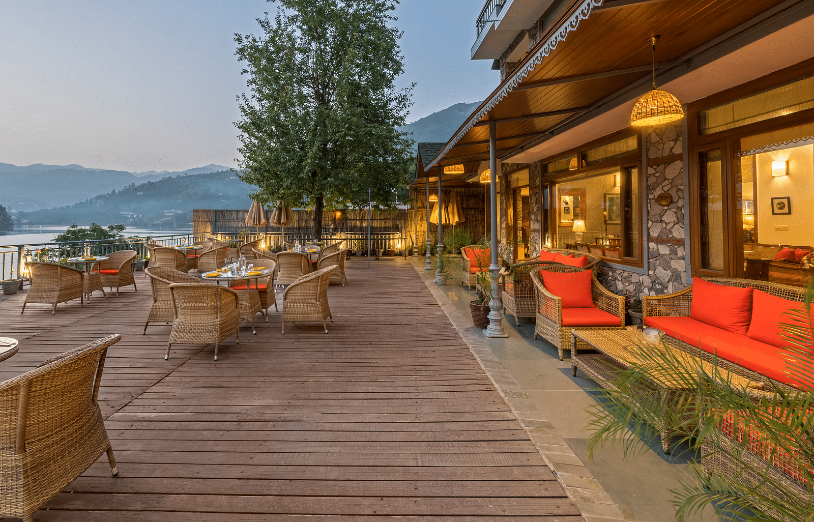 A side angle view of the Outdoor L-Attitude Deck at Fishermen's Lodge, Bhimtal, showcasing its inviting space and scenic surroundings.