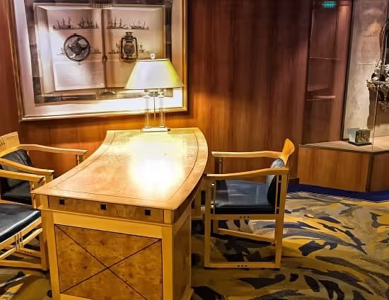 View of a Classic hotel workspace with a wooden desk, lamp, and framed artwork.