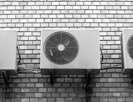 View of air-conditioning units mounted on a brick wall.