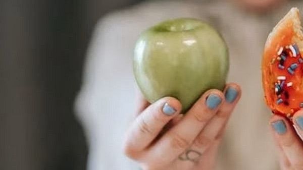 a woman holding an apple in one hand and a doughnut in the other