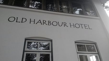 A  black and white image of Old Harbour Hotel with the hotel named written on the wal