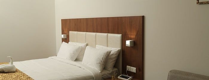 A minimalist hotel room with a stylish bed, neutral tones, and modern furnishings.- Dhanalakshmi Srinivasan Hotels, Perambalur
