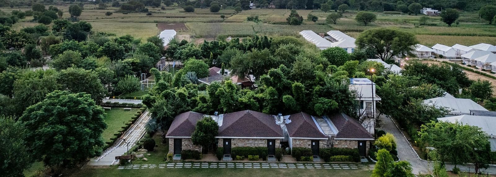 Aerial view of Valley by Grassfield, surrounded by lush greenery with mountains in the background.
