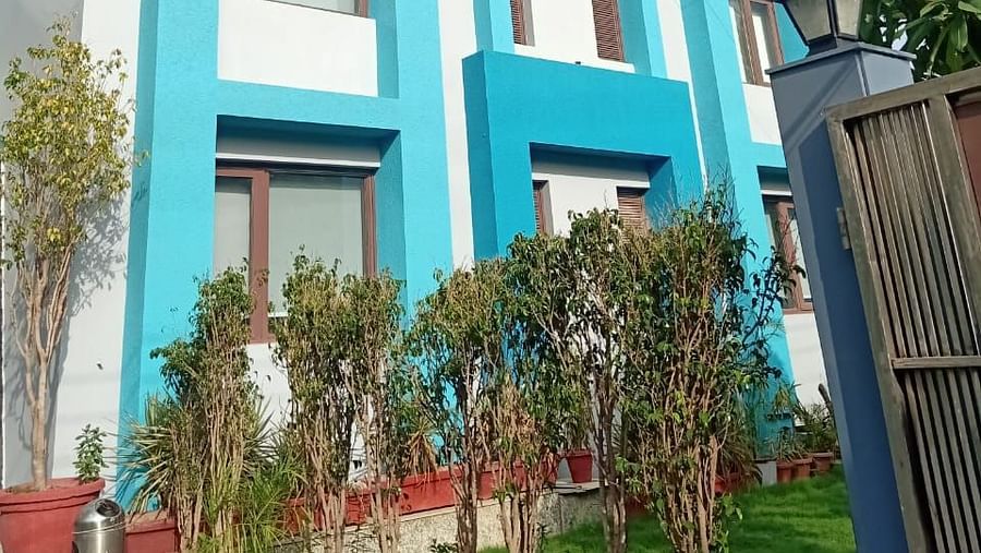An exterior view of a multi-level building with rectangular windows, a sectioned facade, and a fence with greenery at the base - Asian Suites IFFCO Chowk Metro Station, Gurgaon. 