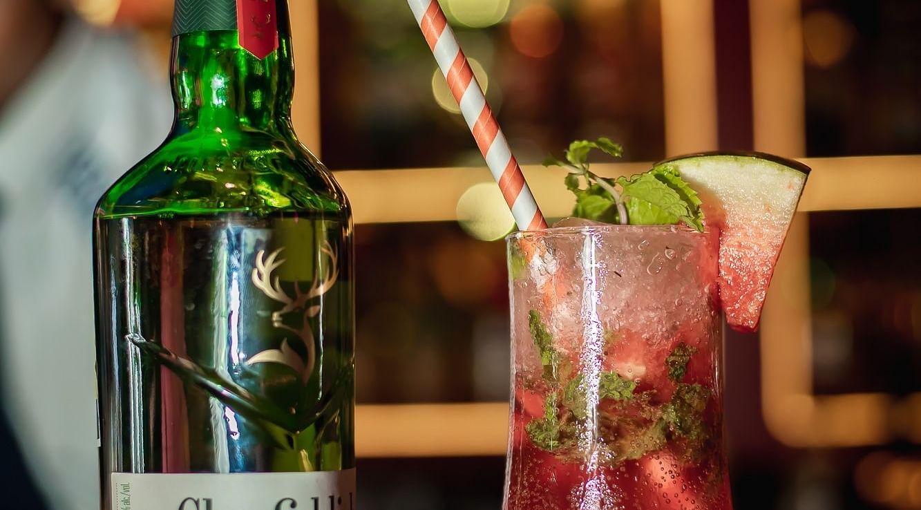 A cocktail beside a bottle of Glenfiddich, with a soft focus on the background.