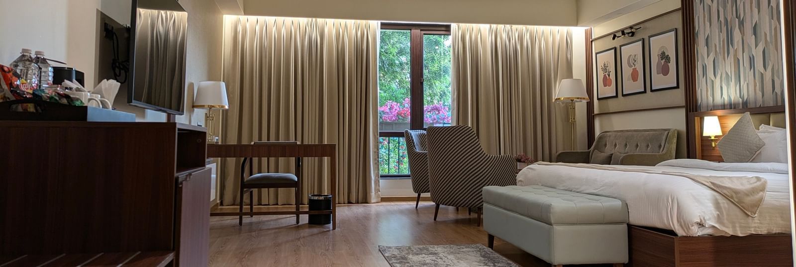The Premium Room at M2 Square by Monday Premium featuring a double bed with the curtains slightly opened showcasing the lush green views from the huge windows.
