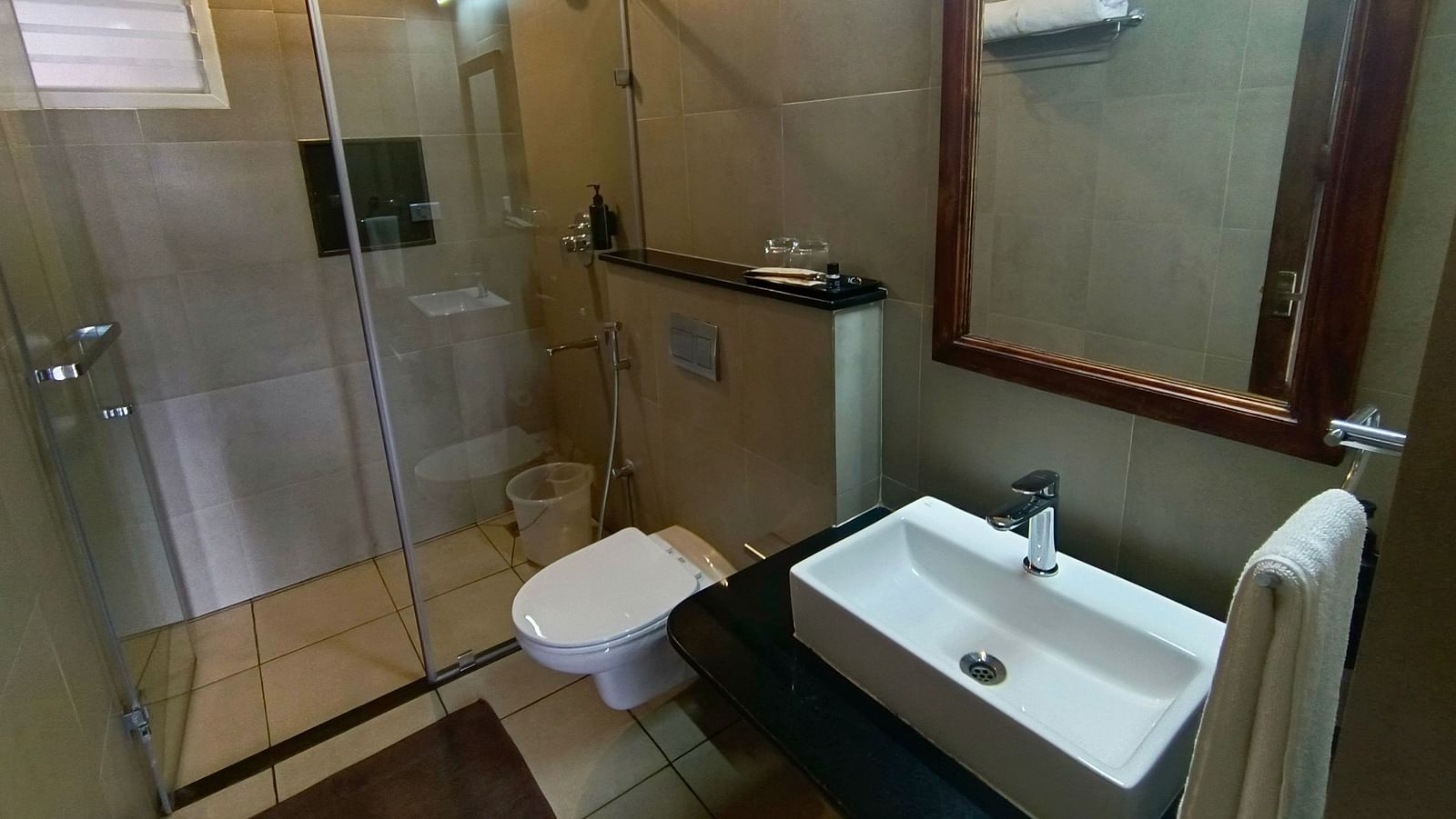 Bathroom with a glass-enclosed shower, sink, and large mirror.