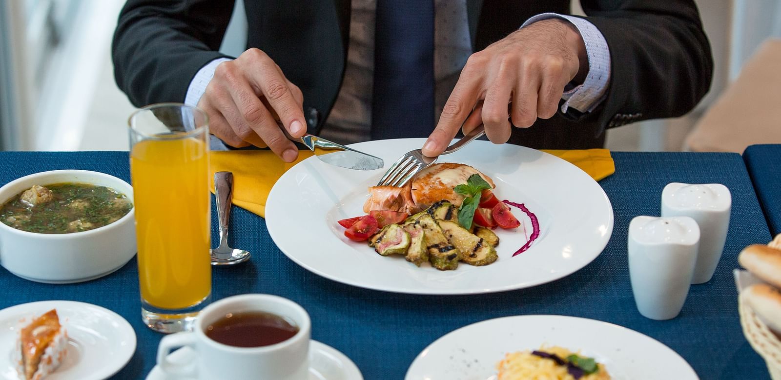A bsinessman dining with a plate of a gourmet food, orange juice, and tea -  Sitara Luxury Hotel in Hyderabad near Ramoji Film City.