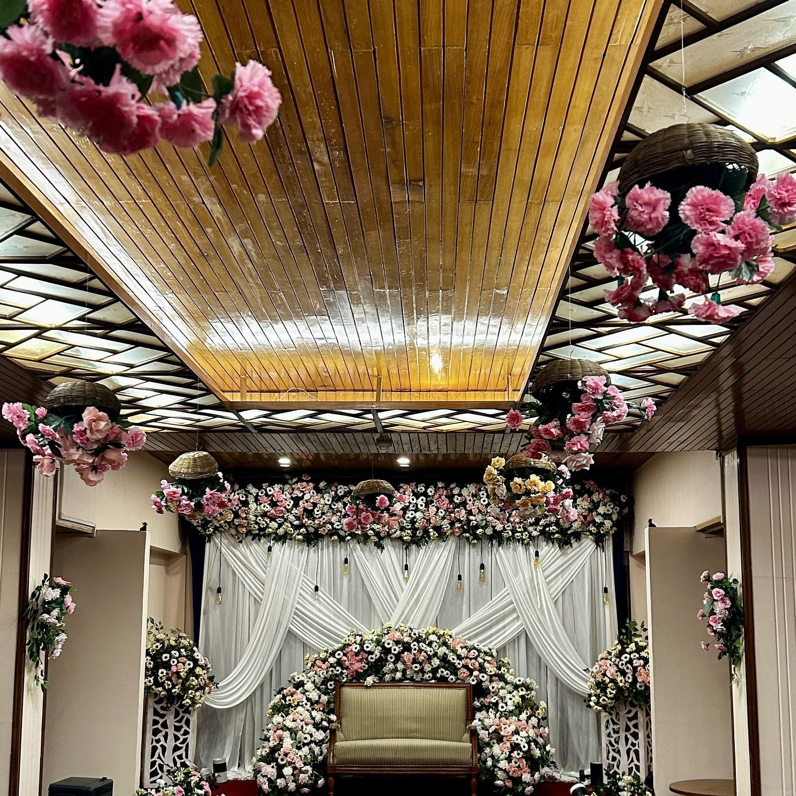 Floral ceiling decor with backdrop setup for wedding ceremony at Cedar Inn, Darjeeling, in an indoor event space.