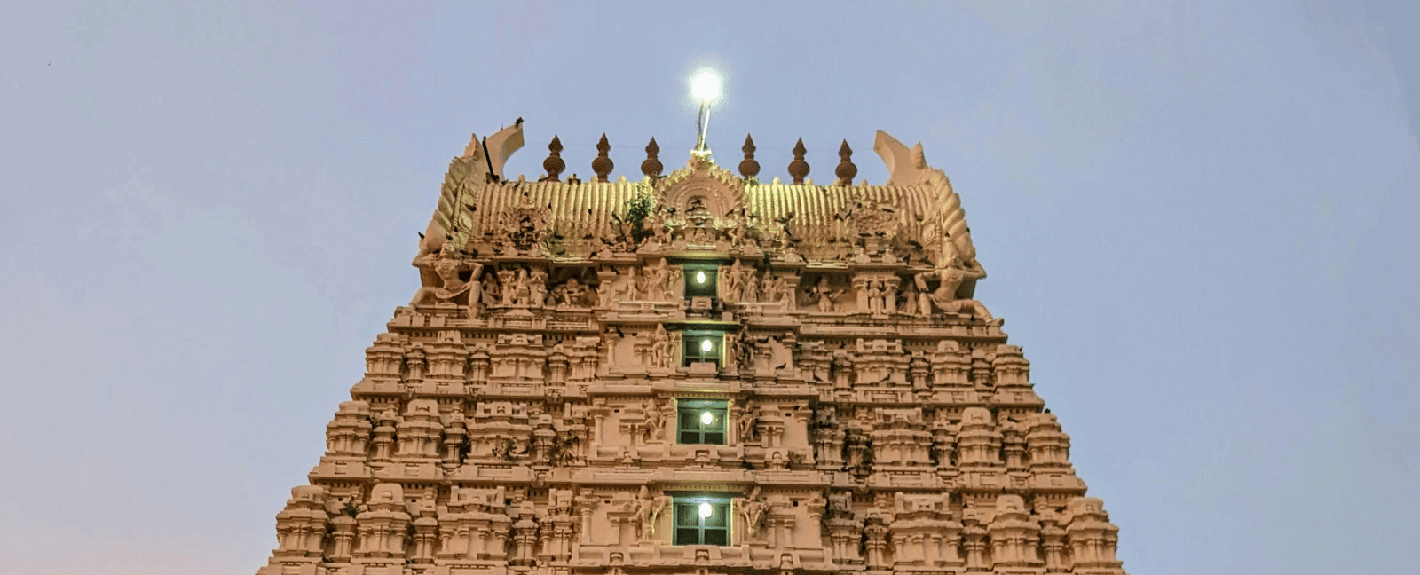 A close up facade shot of a temple featuring the entrance along with a beautiful evening sky in the background.
