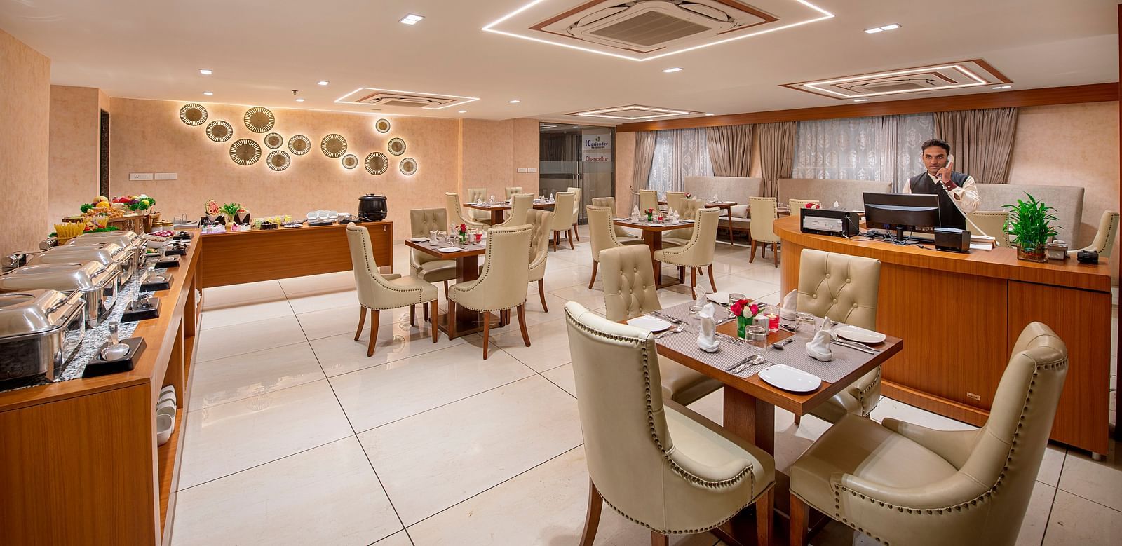 A view of a hotel dining space, showing a mix of table setups - SK Lords Inn Ahmedabad