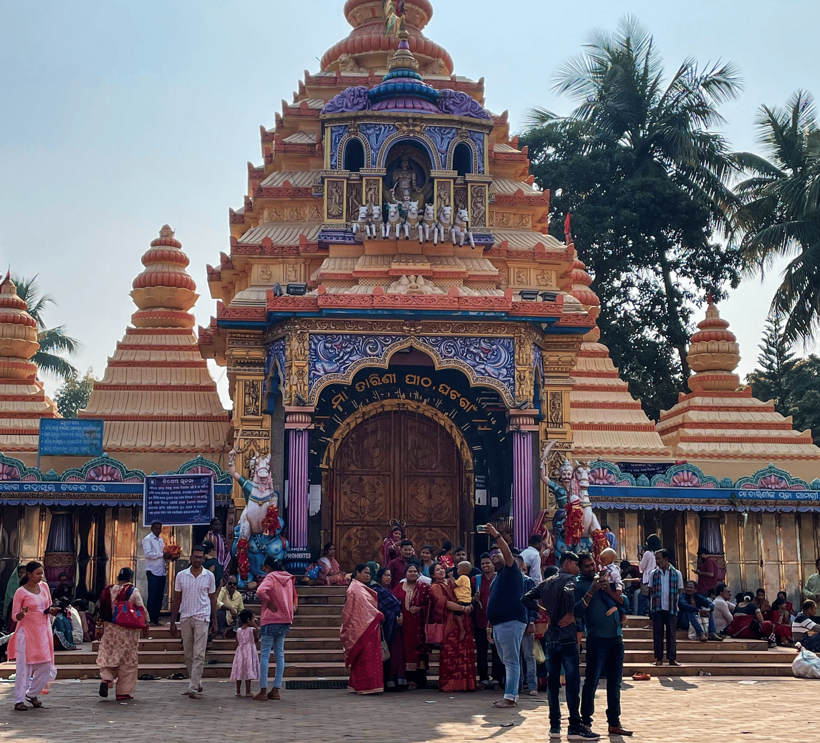 Narayani Temple with a tiered painted spire and devotees in the forecourt, near MAYFAIR Palm Beach Resort, Gopalpur-on-Sea.