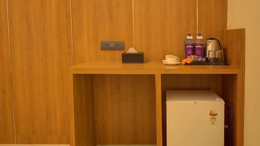 A wooden table in the corner of the Executive Suite with a mini fridge under it and a kettle with small refreshments on the table at Ilara Hotels & Spa, Tada.
