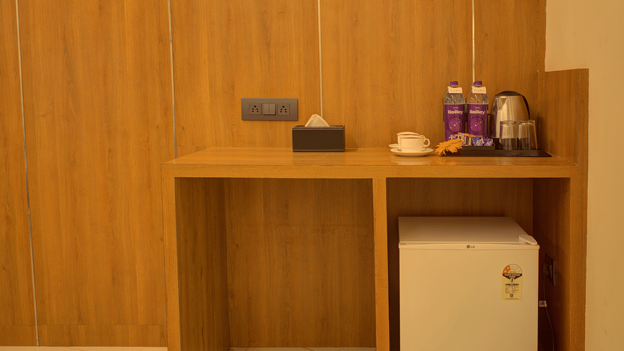 A wooden table in the corner of the Executive Suite with a mini fridge under it and a kettle with small refreshments on the table at Ilara Hotels & Spa, Tada.