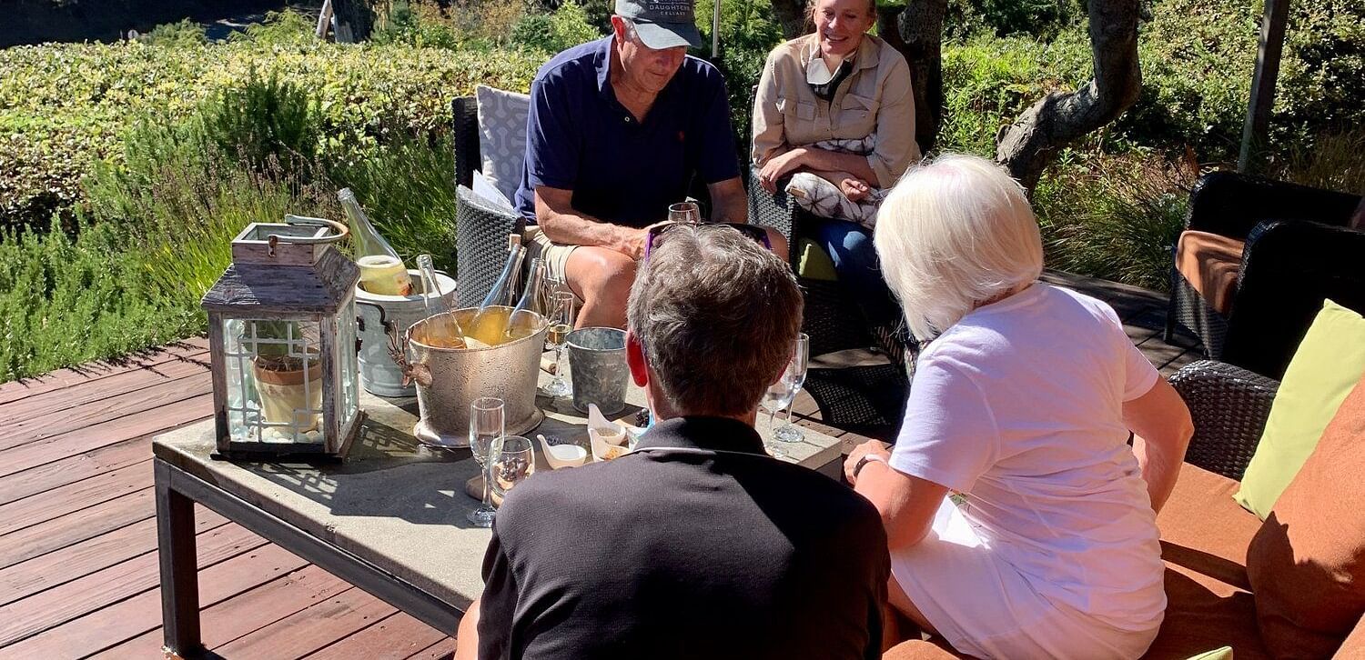 A small group in an outdoor gathering with drinks on a wooden deck