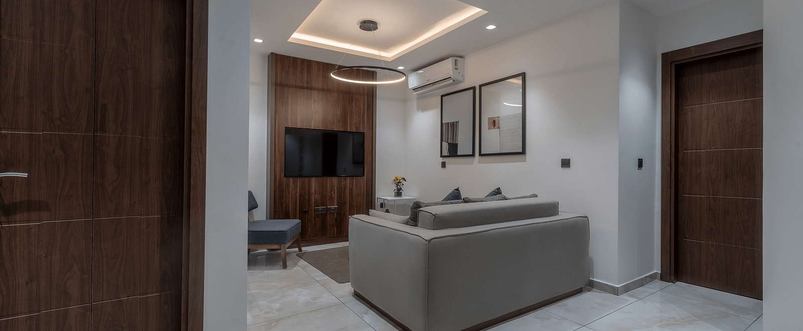 A well-lit, modern Executive Suite featuring a seating area and a closed wooden door.  - The Pelican Hotel, Accra