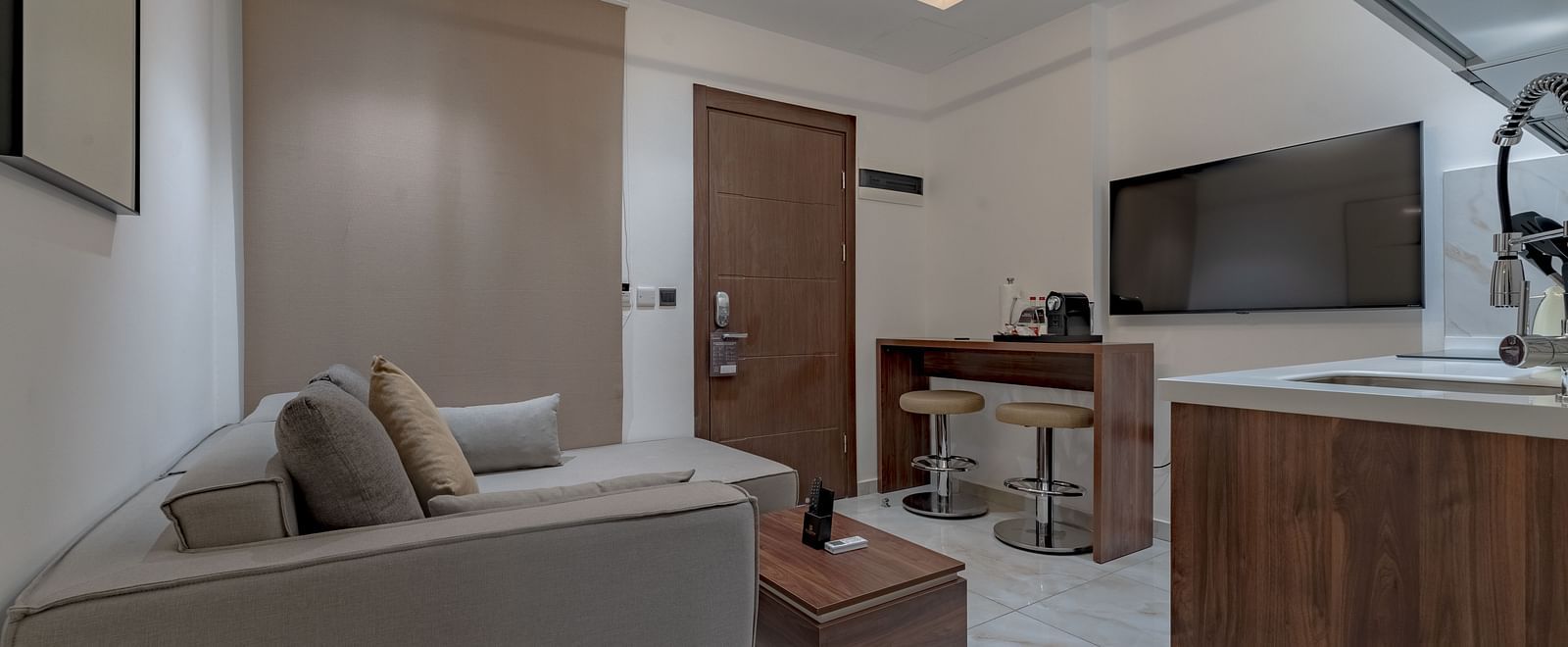 Modern, well-equipped kitchen in a Deluxe Room with wooden cabinetry and stainless steel appliances. - The Pelican Hotel, Accra