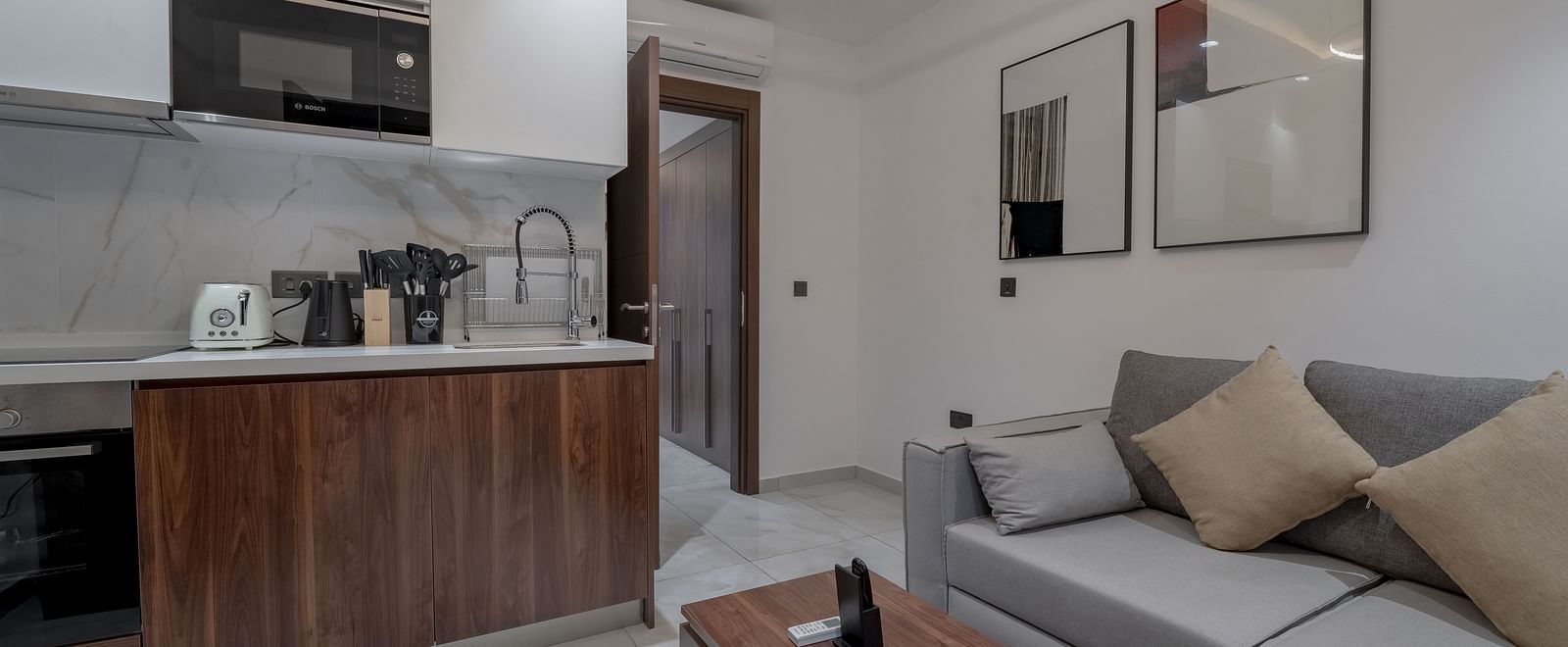 A bright, modern Junior Suite with a sofa, and a kitchenette. - The Pelican Hotel, Accra