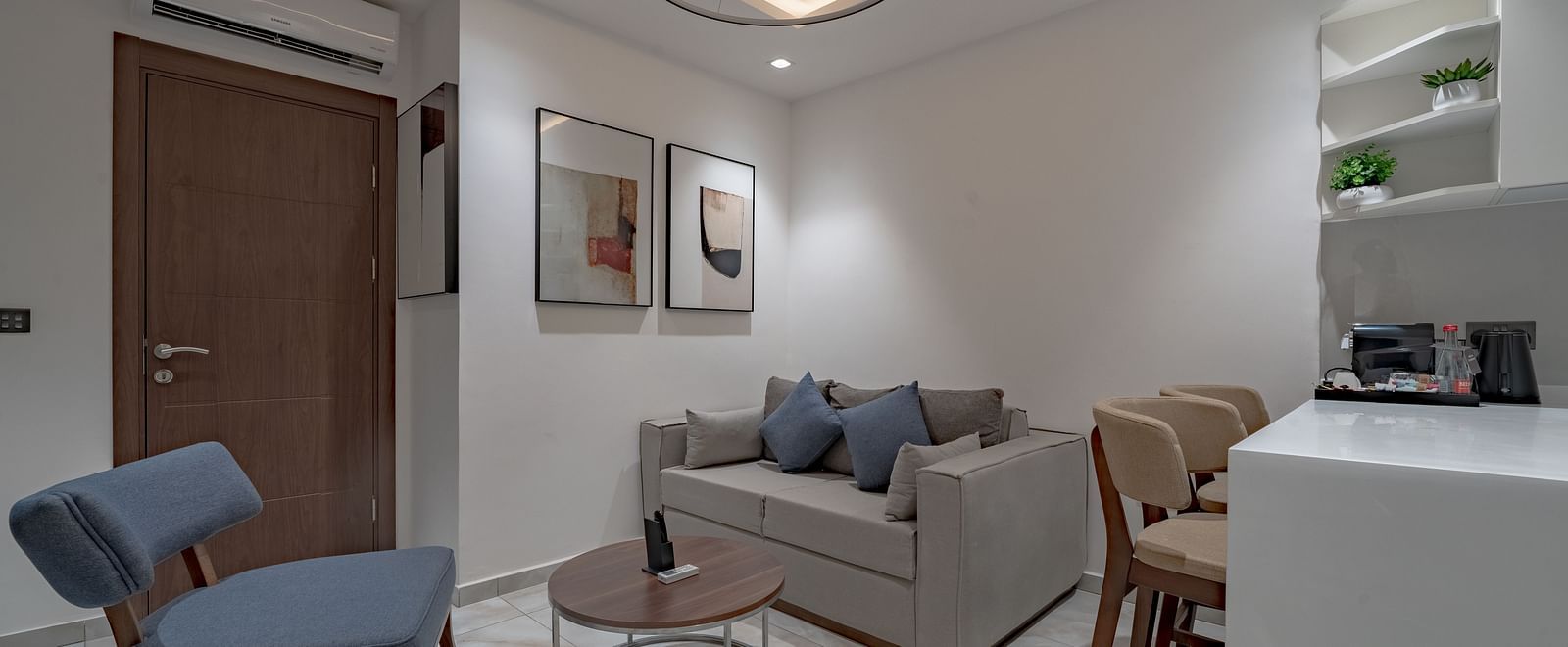 Modern and bright living room of a Junior Suite with sofa, table, and kitchenette. - The Pelican Hotel, Accra