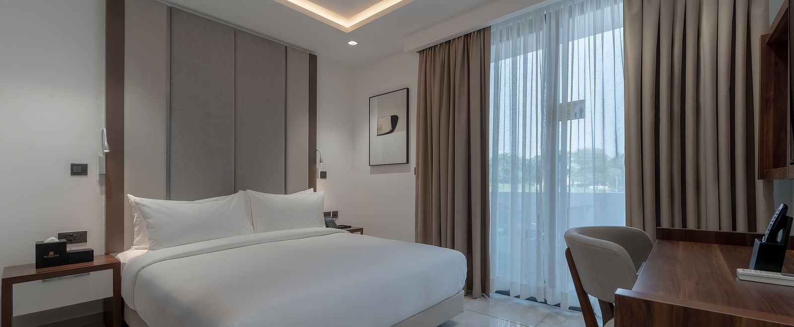 Spacious Standard Room with king size bed, soft lighting, wooden desk, large window, and cozy ambience. - The Pelican Hotel, Accra