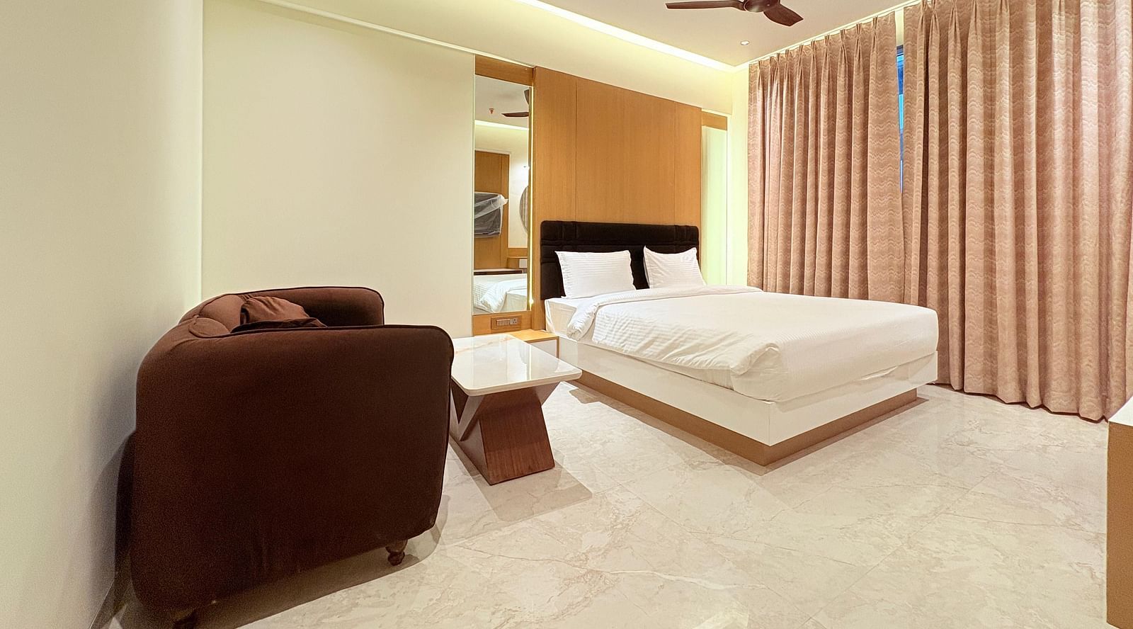 Bedroom with a huge cushioned sofa and a ceiling fan, at Hotel Mumbai House, Vashi.