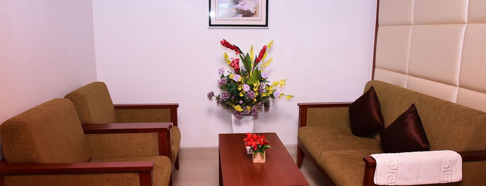 A cosy lounge area with comfortable sofas, a coffee table, and elegant decor for relaxation.- Dhanalakshmi Srinivasan Hotels, Perambalur