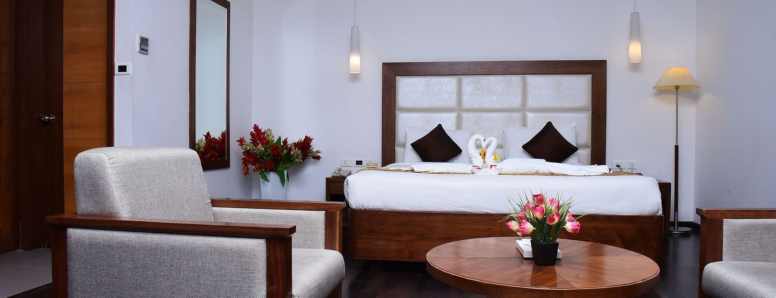A stylish hotel suite with plush seating, warm lighting, and modern decor for a comfortable stay.- Dhanalakshmi Srinivasan Hotels, Perambalur