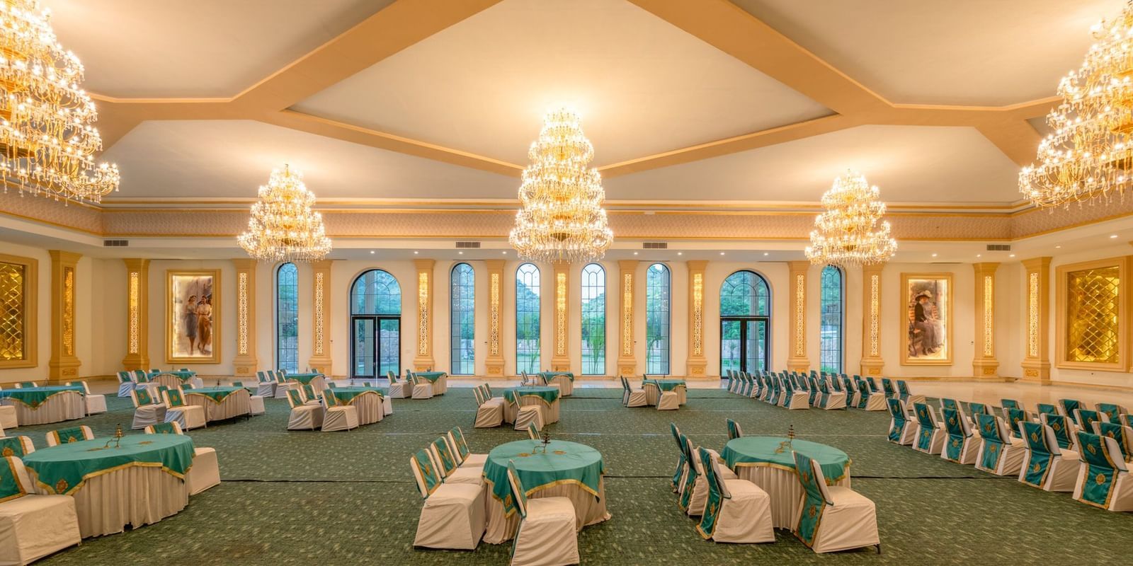 Side view of a banquet hall featuring round tables with chairs and chandeliers elegantly hanging from the ceiling at Valley by Grassfield.