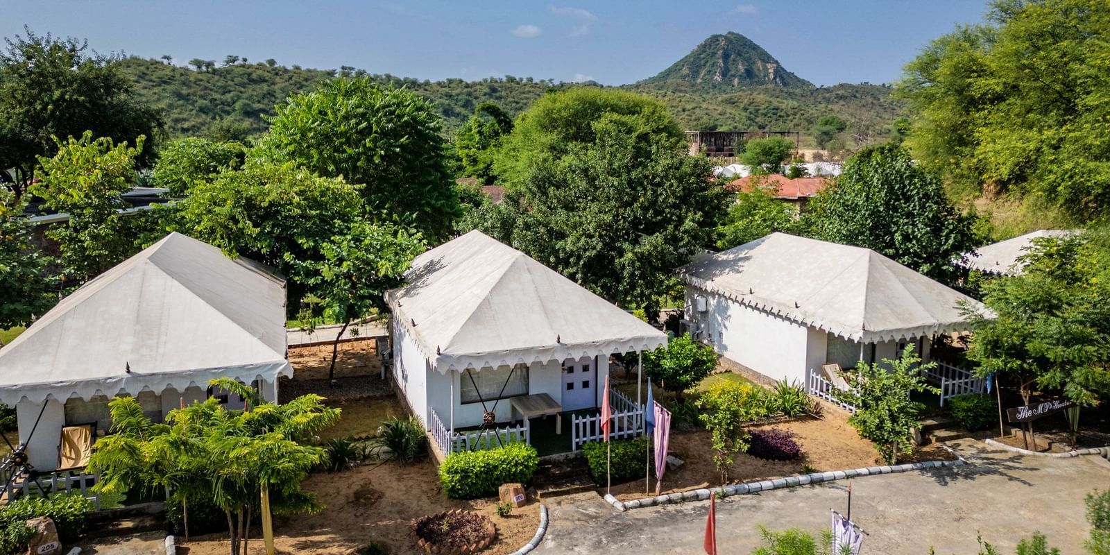 Aerial view of tent-style accommodations at Valley by Grassfield, nestled amidst lush trees and greenery.