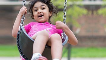 A child enjoying a swing ride with the background being blurred at Caravela Beach Resort