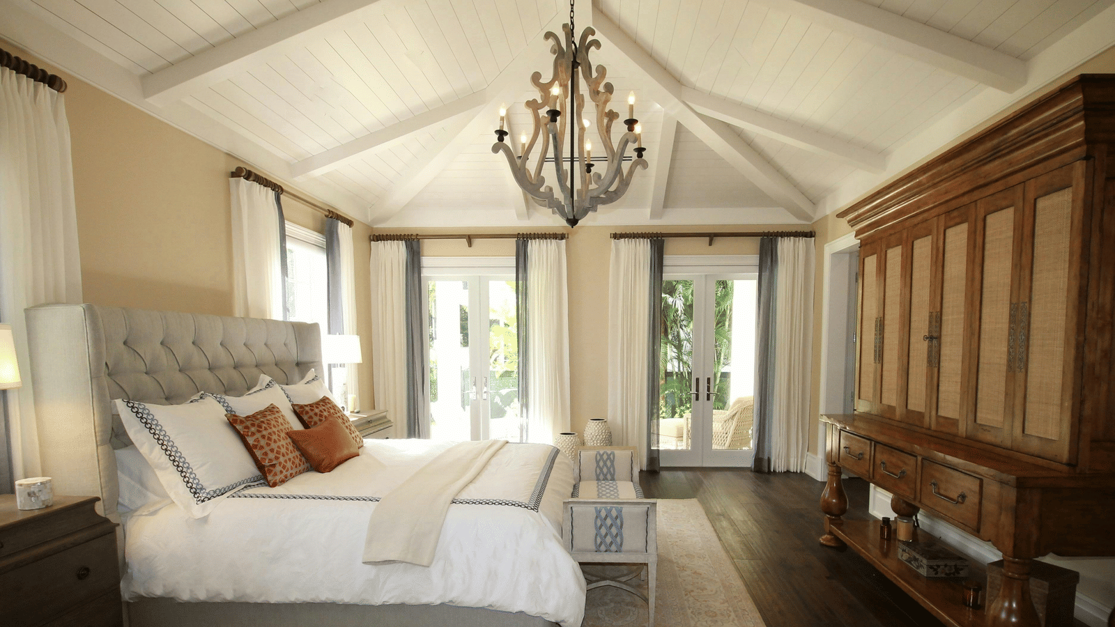 Side view image of the bed with a chandelier hanging over the double bed.