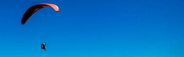 Image of a person paragliding over a mountain range